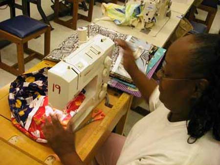 Club Member Francine sews Tailor Made tags on pillowcases.