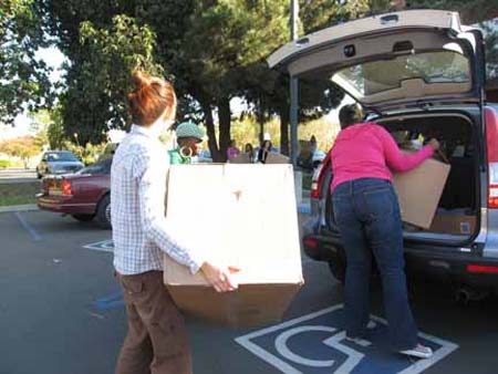 Fashion students help in bring boxes into cars.