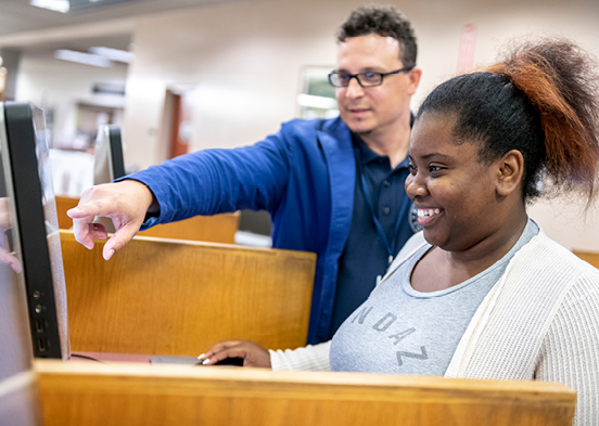 Faculty helping student at library computer