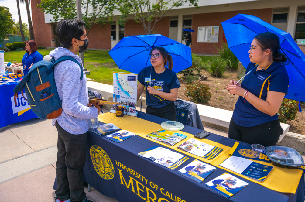 Student talking to university representatives at annual university fair.