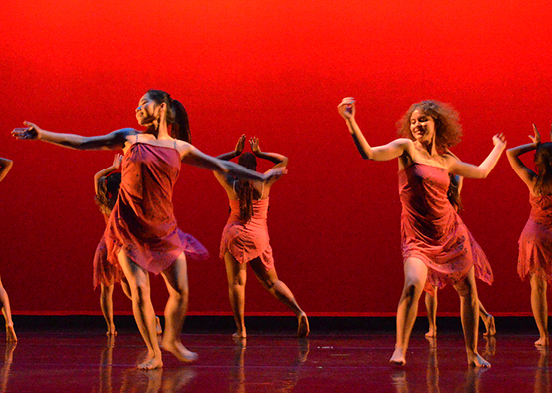 Performers dancing on red-colored stage.