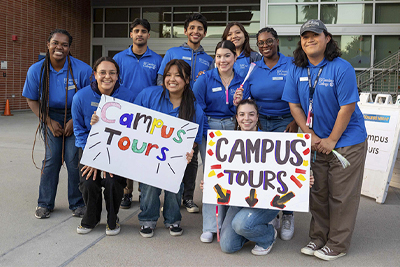 Ambassadors smiling and holding Campus Tours signs
