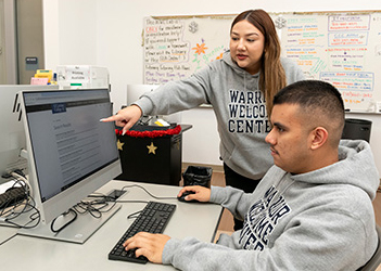 One student helping another student at the computer