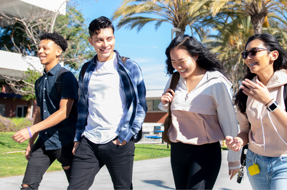 Four students walking and smiling.