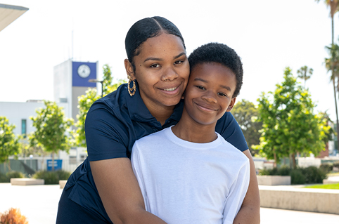 CARE student hugging her son from behind and smiling.
